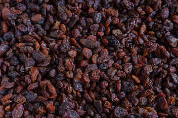 Background of dark, bright and large raisins scattered on the table.