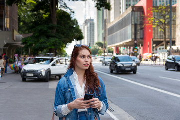 Cool redhead woman with smart phone at Paulista Avenue (Avenida Paulista), São Paulo, Brazil