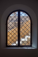 Arched window with bars that overlooks the courtyard of the old fortress. Window in castle