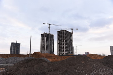 Tower cranes constructing a new residential building at a construction site against blue sky....
