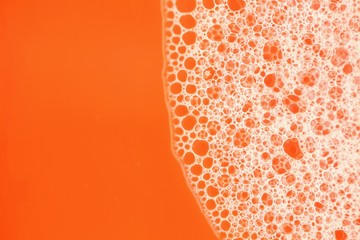 Foam close-up bubbles on a bright orange background. Orange soap foam macro background. Soap bubbles orange bright color with a white gradient. Bath foam. Cleanliness and order.