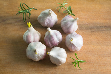 Garlic cloves and rozmarine on a vintage wooden background.