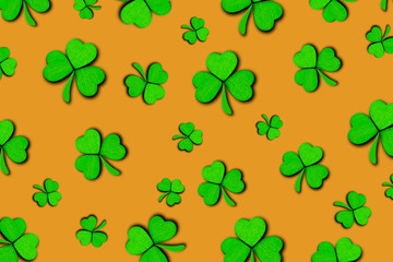 Pattern of green clovers or shamrocks isolated on orange background. St. Patrick's Day Holiday concept. Spring background.