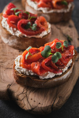 Sandwich with soft cheese and baked red bell pepper on a wooden board.