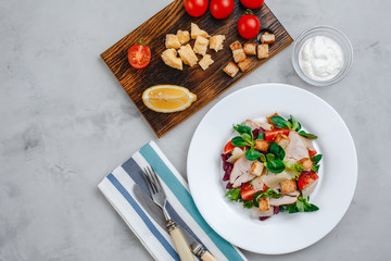 Fototapeta na wymiar Fresh Caesar salad with delicious chicken breast, spinach, cabbage, arugula, Parmesan and cherry tomatoes on a light background. Caesar sauce, lemon, broken cheese. The concept of healthy and dietary 