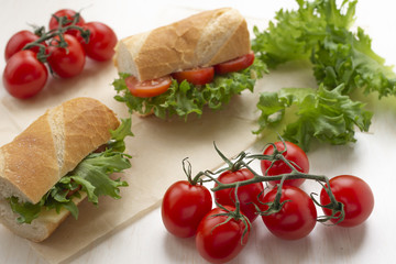 Fototapeta na wymiar sandwiches with lettuce, tomatoes and cheese, on a light background, with cherry tomatoes on a branch