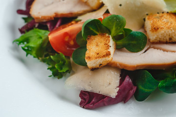Fresh Caesar salad with delicious chicken breast, spinach, cabbage, arugula, Parmesan and cherry tomatoes on a light background. Caesar sauce, lemon, broken cheese. The concept of healthy and dietary 