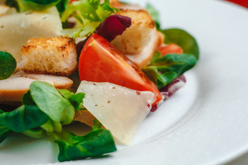 Fresh Caesar salad with delicious chicken breast, spinach, cabbage, arugula, Parmesan and cherry tomatoes on a light background. Caesar sauce, lemon, broken cheese. The concept of healthy and dietary 