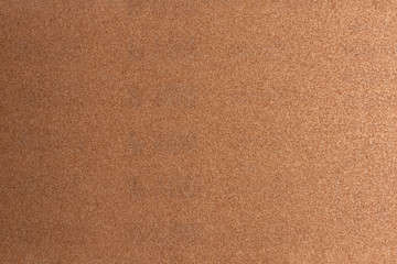 Background made of brown sandpaper, illuminated by a soft light from the right.