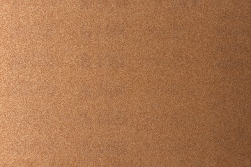 Background made of brown sandpaper, illuminated by a soft light from the left.