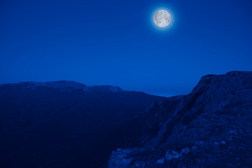 Mesmerizing picturesque mountain landscape with a full moon at night. Concept of pristine nature and the mystic moon. Advertising space