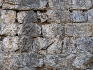 The medieval wall is lined with rough gray stone. Stone vertical retro background.
