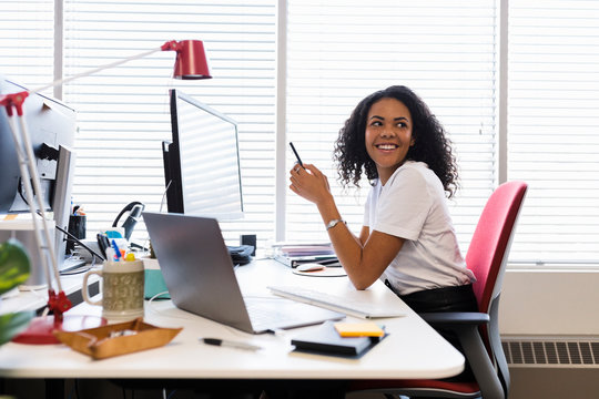 Smiling, confident creative businesswoman using smart phone at office 