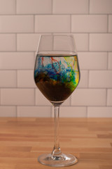 Full wine glass with stem filled with water and food coloring swirling 
