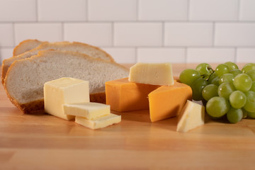 Cheese bread butter and green grapes on butchers wood table healthy snack options 