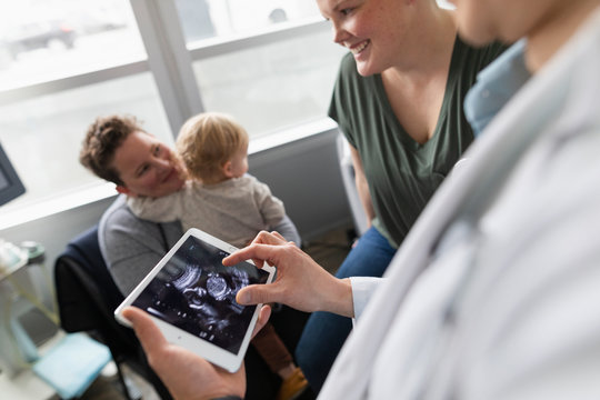 Pediatrician showing mothers ultrasound scan on digital tablet