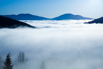 Fototapeta na wymiar Thick white fog among mountain peaks