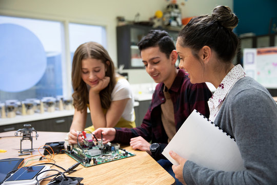 Junior high teacher and students assembling electronics circuit board 