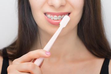 Happy woman clean teeth with dental braces by pink brush. Brackets on the teeth after whitening....