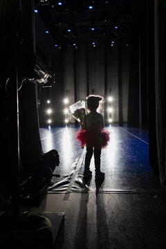 Silhouette cute girl ballerina holding bouquet off stage