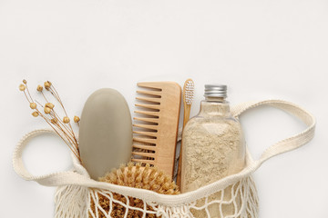 Fototapeta na wymiar Body scrub, soap, wooden comb, beech toothbrushes, body brush in an eco shopping bag on light background. Top view, Flat lay. Skin care, body treatment concept.