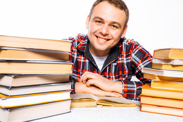 Young friendly male teacher on a white background with books smiles and looks into the frame.