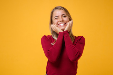 Pretty young blonde woman girl in casual clothes posing isolated on yellow orange background studio portrait. People emotions lifestyle concept. Mock up copy space. Put hands prop up on chin blinking.