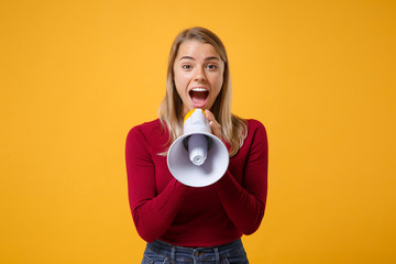 Excited young blonde woman girl in casual clothes posing isolated on yellow orange wall background studio portrait. People sincere emotions lifestyle concept. Mock up copy space. Scream in megaphone.