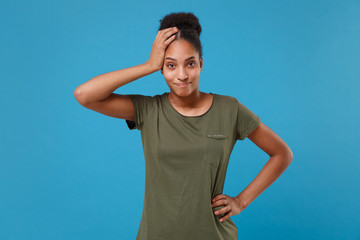 Bewildered young african american woman girl in casual t-shirt posing isolated on bright blue wall background in studio. People lifestyle concept. Mock up copy space. Looking camera, put hand on head.