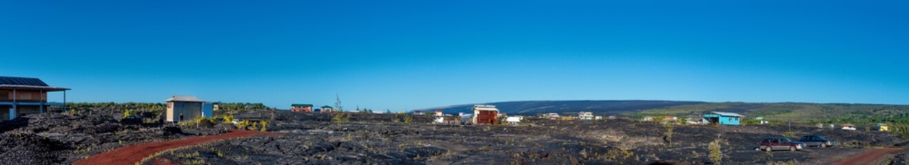 Fototapeta na wymiar Panoramic view of a small village on a field of lava flows in Big Island Hawaii.