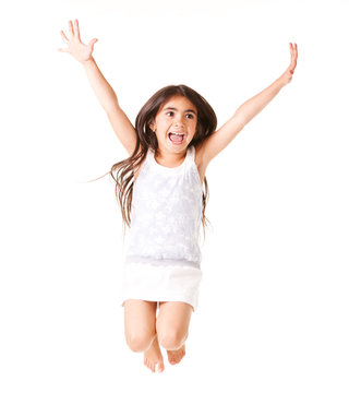 Little Girl In White Dress Laughing And Posing In Jump, Stretching Out Her Arms Up, Isolated On White Background