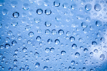 Backdrop glass covered with drops of water. Photo closeup with white and light blue background