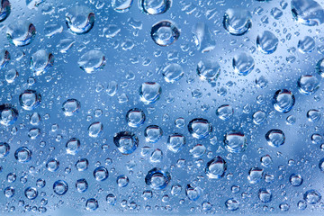Backdrop glass covered with drops of water. Photo closeup with white and light blue background
