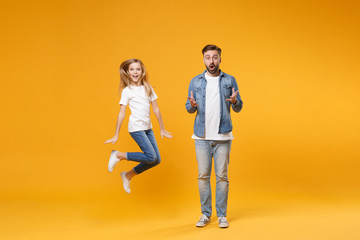 Excited amazed bearded man in casual clothes have fun with child baby girl. Father little kid daughter isolated on yellow background. Love family parenthood childhood concept. Spreading hands jumping.