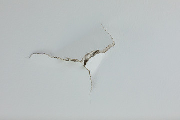 Puncture crack hold in ceiling wall of white painrtd drywall - obrazy, fototapety, plakaty