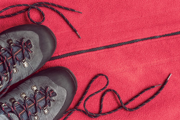Trekking boots on the red background of sports clothing, top view, copy space