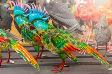 Colorful metallic decorative parrots on the wooden background