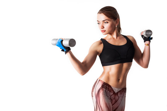 Pretty young muscular woman fitness instructor in sportswear holding iron dumbbells in her hands on a white background. Regular training concept. Advertising space