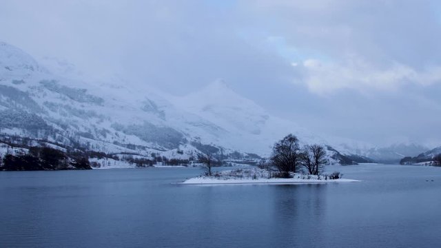 footage of snow falling over loch leven and eilean nam ban, an island in the loch, in the argyll region of the highlands of scotland during winter
