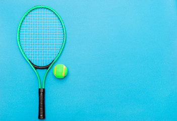 Tennis ball and racket on blue background. Sport equipment. Flat lay.