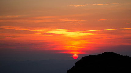 beautiful sunset in mountains with silhouette of a rock