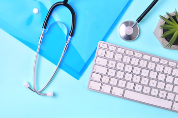 Doctor workplace with medical stethoscope, computer keyboard and folder.