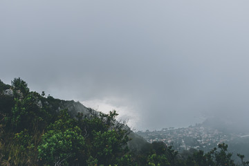 The panoramic view of an old French village named Èze on the coast of the Mediterranean Sea and the Alps mountains under a cloud on a gloomy day (Côte d'Azur)