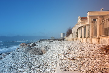 sea ​​with sandy beach and rocks with a view of the fiat tower in massa carrara in tuscany in front of the don gnocchi hospital - obrazy, fototapety, plakaty