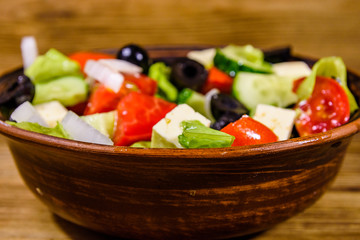 Ceramic plate with greek salad on wooden table