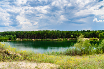 Obraz na płótnie Canvas View on a lake in the abandoned sand quarry and dramatic sky