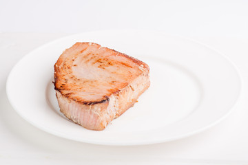 grilled tuna fish steak on a white plate with a place for garnish
