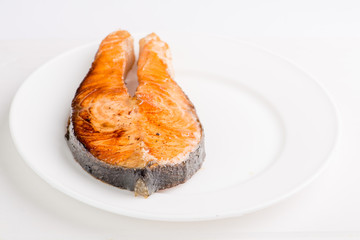 grilled salmon fish steak on a white plate with a place for garnish