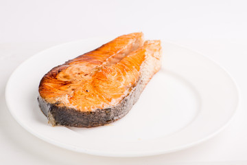 grilled salmon fish steak on a white plate with a place for garnish