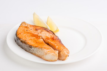 grilled salmon fish steak on a white plate with a place for garnish